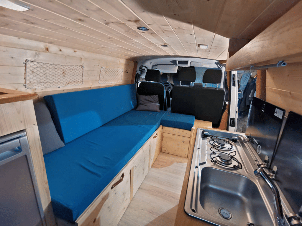 Captivan location d'un van t6 Volkswagen aménagé avec canapé lit bleu tout confort et cuisine équipée électricité et eau pour vacances ou week-end