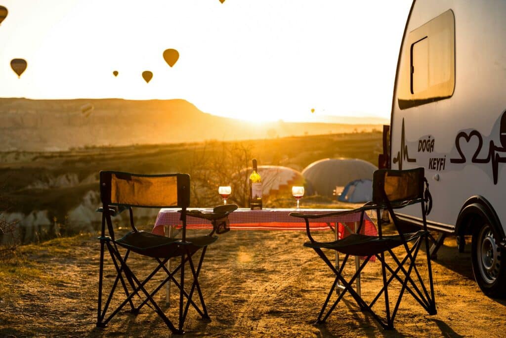 Une table et des chaises pliables de camping-car qui ont vue sur des montgolfières.
